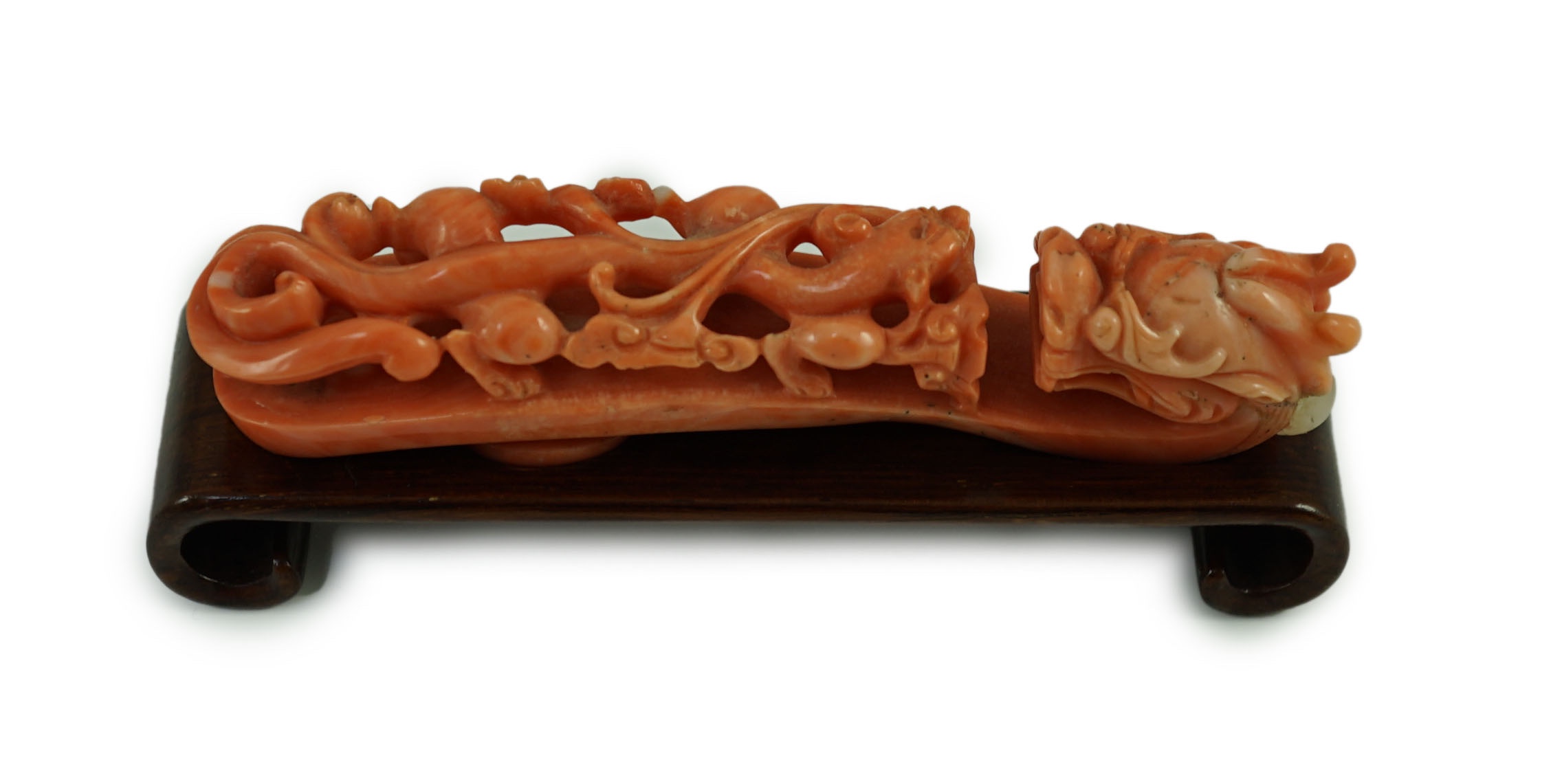 A rare Chinese coral 'dragon' belt hook 18th/19th century, 9.2 cm long, small loss to dragon horn, wood stand